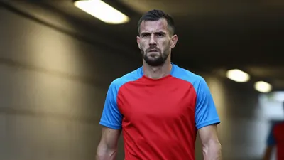 A 35-year-old West Bromwich Albion defender, 5'10" with a rugged build, in a plain unmarked red and sky blue polyester...