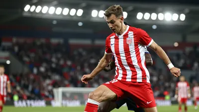 A photorealistic image of a 23-year-old, 5'9'' tall, athletic build, forward, wearing a red and white striped jersey...