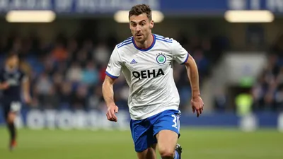 A 30-year-old, athletic, anonymous Leyton Orient player, wearing a white jersey with a blue stripe, and blue shorts, with...