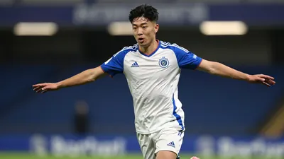 A tight action crop of an anonymous 25-year-old Leyton Orient midfielder in a white jersey with blue sleeves and a blue...