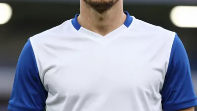 A close-up shot of a Leyton Orient player in a white shirt with blue sleeves, taken with a 50mm f/1.4 lens, with a...